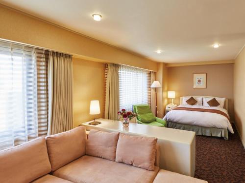 a hotel room with a bed and a couch at Hotel Agora Osaka Moriguchi in Osaka