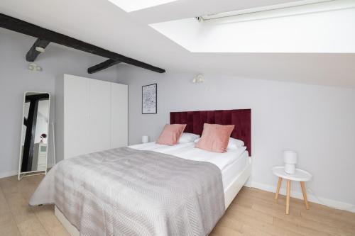 um quarto branco com uma cama grande e almofadas cor-de-rosa em Apartment with 2 Bedrooms and Desks in the Center of Cracow by Renters em Cracóvia