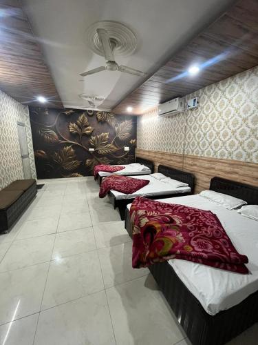 four beds lined up in a row in a room at Ganpati hotal in Amritsar