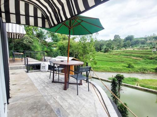 a table and chairs with an umbrella on a patio at Shine River in Ciwidey