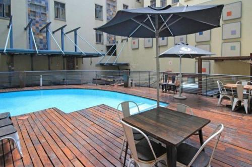 een patio met een tafel, een parasol en een zwembad bij Ducks Place @ 214 Mapungubwe in Johannesburg