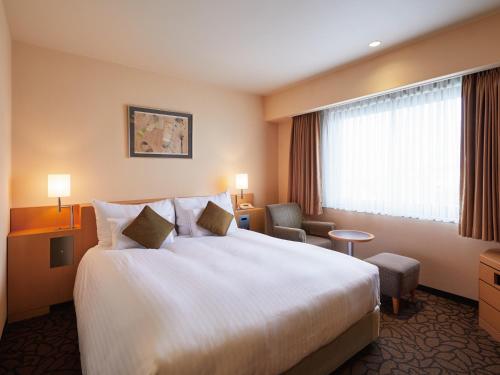 a hotel room with a large bed and a window at Hotel Agora Osaka Moriguchi in Osaka
