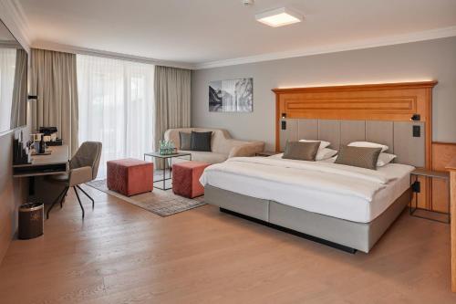 a bedroom with a bed and a couch and a desk at Hotel EDELWEISS Berchtesgaden Superior in Berchtesgaden