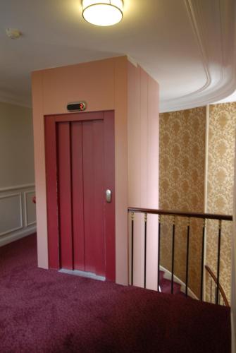 a red door in a room with purple carpet at Hôtel Bellevue et du Chariot d'Or in Paris