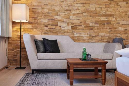 a living room with a couch and a brick wall at Hotel EDELWEISS Berchtesgaden Superior in Berchtesgaden