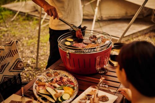 uma pessoa cozinhando comida em um pote sobre uma mesa em Laforet Glamping Field Hakuba em Hakuba