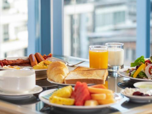 曼谷的住宿－宜必思曼谷素坤逸 24 号酒店，餐桌上摆放着早餐食品和橙汁盘