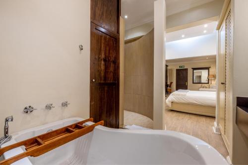 a bathroom with a tub and a bedroom with a bed at Sheppard Boutique Hotel in Nelspruit