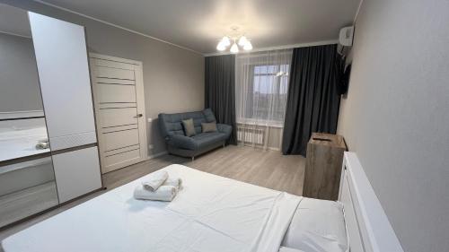 - une chambre avec un lit et une chaise bleue dans l'établissement ЖК Ауэзова1, à Kökşetaw