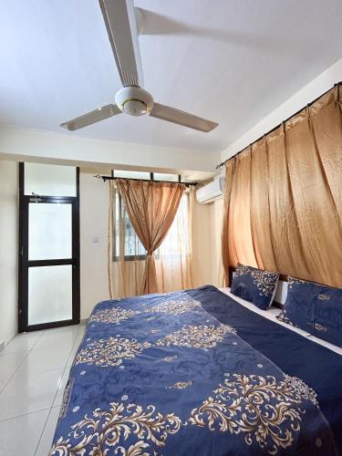 a bedroom with a blue bed with a ceiling fan at Karibu house in Dar es Salaam