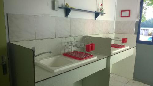 La salle de bains est pourvue de 2 lavabos et de paniers rouges sur le comptoir. dans l'établissement Camping des 2 Rives- Chambres, à Étang-sur-Arroux