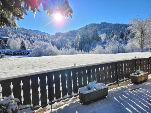 uma cerca coberta de neve com um campo coberto de neve em Appartement Helios em Les Gets