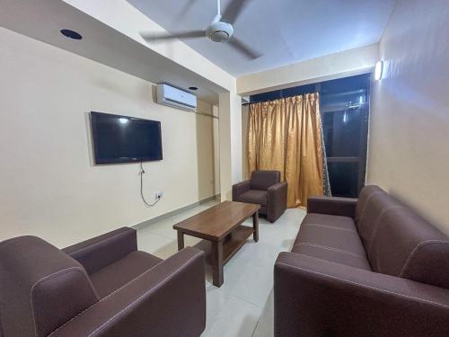 una sala de espera con sofás, mesa y TV en Karibu house en Dar es Salaam