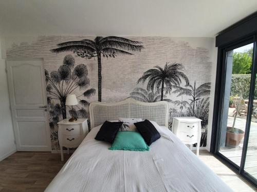 - une chambre avec un lit blanc et des palmiers sur le mur dans l'établissement 4 pers / maison calme piscine / 15mn mythique circuit des 24h du Mans, au Mans