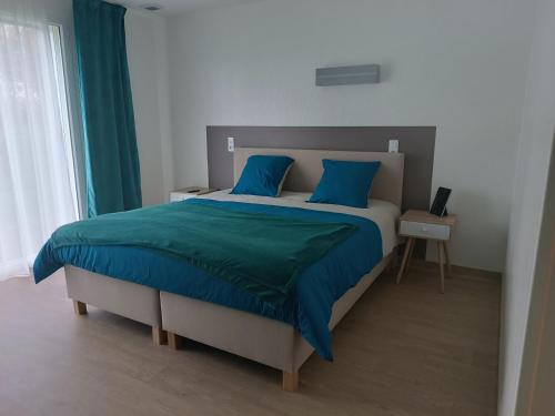 1 dormitorio con 1 cama grande con almohadas azules en Relais Les Rives du Lac en Coulonges-sur-Sarthe