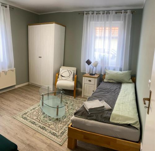 ein Schlafzimmer mit einem Bett, einem Stuhl und einem Glastisch in der Unterkunft Apartment Am Mittelpunkt Deutschlands in Niederdorla