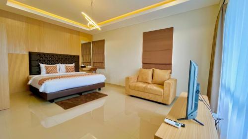 - une chambre avec un lit, une télévision et une chaise dans l'établissement Front One Hotel Gombong, à Gombong