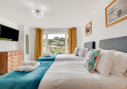 Duas camas num quarto com uma janela em Mizzen Cottage em Looe