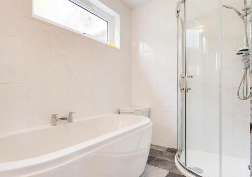 uma casa de banho branca com uma banheira e uma janela em Mizzen Cottage em Looe