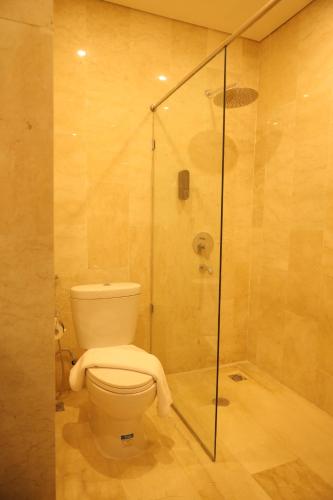 La salle de bains est pourvue de toilettes et d'une douche en verre. dans l'établissement Salatin Hotel Palembang, à Palembang