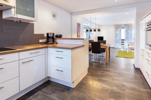 a kitchen with white cabinets and a dining room at Ferienwohnungen Haus Birgit in Günzgen