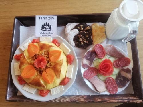 uma bandeja com um prato de comida com frutas e carnes em Tarin zov em Kaludjerske Bare
