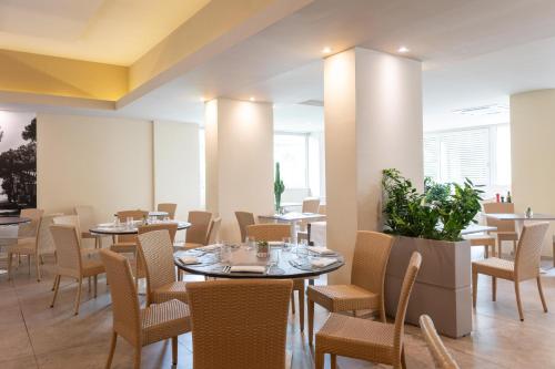 una sala da pranzo con tavoli, sedie e finestre di Perla Verde Hotel a Milano Marittima