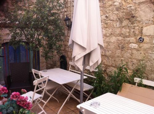 a white umbrella sitting next to a table and chairs at Hôtel du Parc in Malakoff