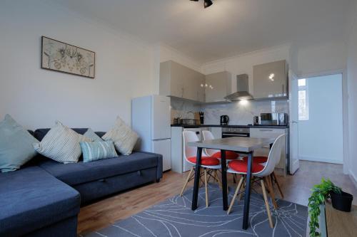 uma sala de estar com um sofá, uma mesa e cadeiras em Lovely 2-bed Highbury Home em Londres