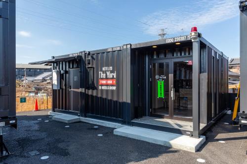 a black building with a door in a parking lot at HOTEL R9 The Yard 荒尾 in Arao