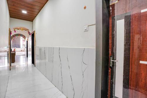 a hallway with white marble walls and a door at Hotel Sai Lodging I - Nr Nashik Railway Station in Nashik