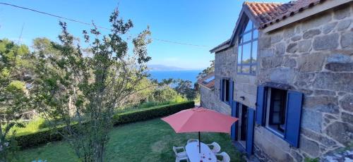 a patio with a pink umbrella and chairs and a building at Casa Campo de Cortes in Muros