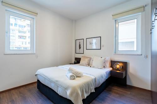 a bedroom with a large bed with two windows at Harbor Apartments in Larnaca in Larnaka