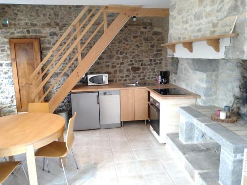 een keuken met een tafel en een tafel en een trap bij Gîte Les Pommiers in Montchaton