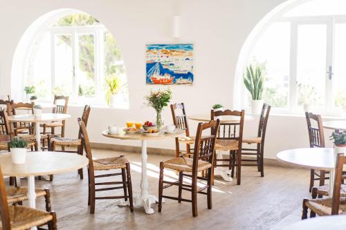 a dining room with tables and chairs and windows at Pelican Hotel in Mýkonos City