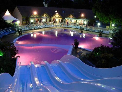 a large swimming pool with purple water at night at De La Terre Locan in Saint-Brevin-les-Pins
