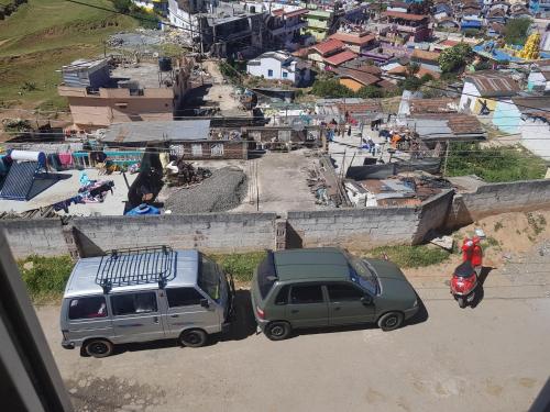 dois veículos estacionados numa estrada de terra ao lado de uma cidade em Salu comforts em Ooty