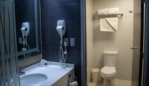 ein Badezimmer mit einem Waschbecken, einem WC und einem Spiegel in der Unterkunft Hotel Araiza San Luis R.C. in San Luis Río Colorado