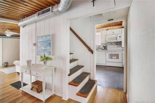 a white room with a staircase and a kitchen at Cozy Beach - Direct Waterfront! in East Haven