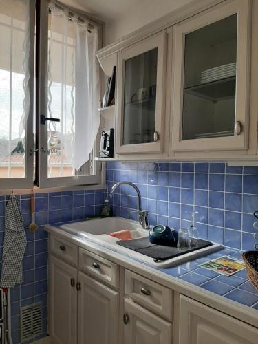 een keuken met witte kasten, een wastafel en blauwe tegels bij Front de mer Golfe de Saint-Tropez in Sainte-Maxime
