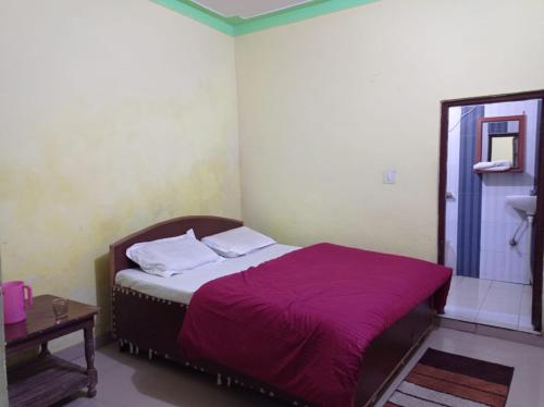 バドリーナートにあるBadrinath House by Prithvi Yatra Hotelのベッドルーム(紫の毛布付きのベッド1台付)