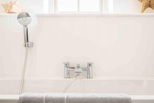 y baño con bañera con cabezal de ducha. en Sea Chest, Salcombe Waterside Apartment, en Salcombe
