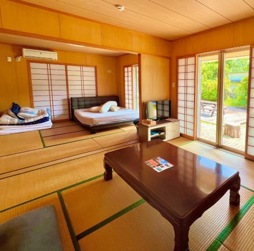 a living room with a bed and a coffee table at totono house 満天の星空 テントサウナ BBQ 元有形文化財を1棟貸切 うるま市 浜比嘉島 in Uruma