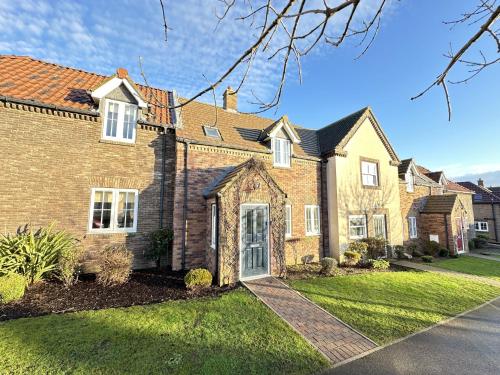 a large brick house with a yard at Willow Cottage - Part of the The Bay Filey Holiday Village with pool, gym and direct beach access, pub, restaurant, tennis and meadows walks in Reighton