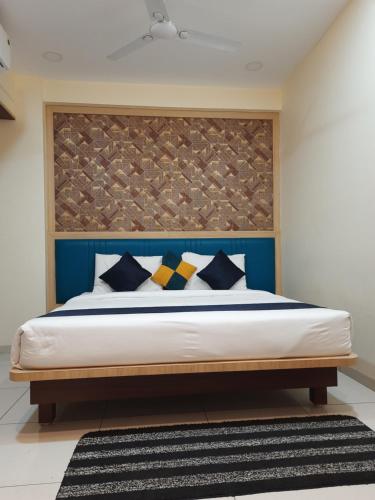 a bedroom with a bed with a blue headboard at Hotel Sarika International in Indore