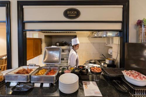 a chef standing in a kitchen preparing food at Cape House Hotel, Bangkok in Bangkok