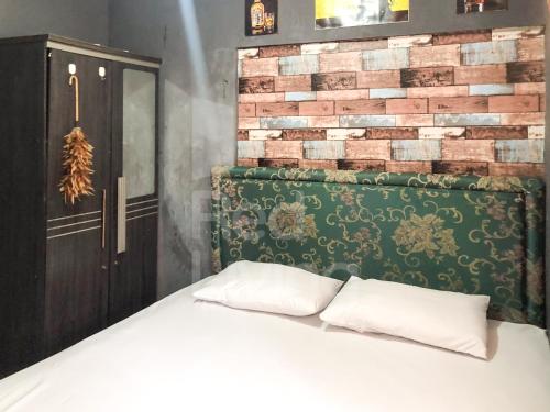 - un lit avec deux oreillers devant un mur en briques dans l'établissement RedLiving The Golf Apartement Modernland - Maria Room Tower Red, à Buaran