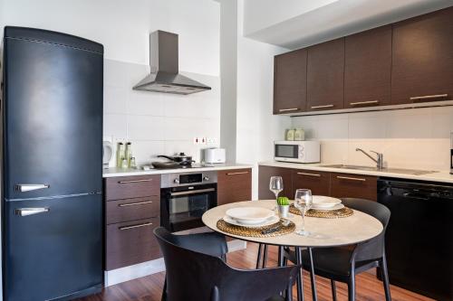 a kitchen with a table with chairs and a black refrigerator at Harbor Apartments in Larnaca in Larnaka