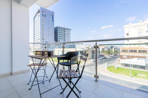a balcony with a table and chairs and a view of a city at Harbor Apartments in Larnaca in Larnaka