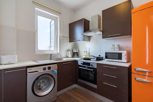 a kitchen with a washing machine and a microwave at Harbor Apartments in Larnaca in Larnaka